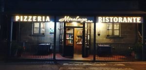 Ingresso di una pizzeria ristorante illuminato di sera.
