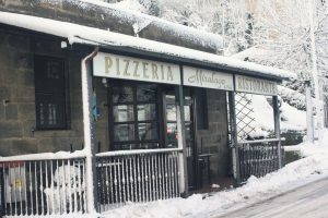 Ingresso di una pizzeria innevata.