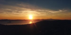 Tramonto su un lago con colline all'orizzonte.