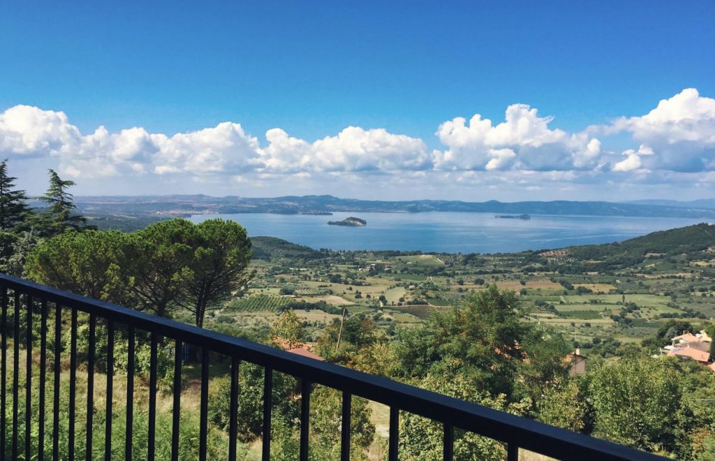 Vista panoramica su lago e campagna con cielo nuvoloso.