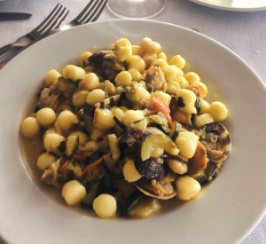 Gnocchetti con vongole e verdure in piatto bianco.