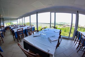Ristorante con tavoli apparecchiati e vista panoramica.