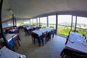 Ristorante con tavoli apparecchiati e vista panoramica.