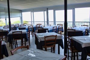 Sala ristorante con tavoli apparecchiati e vista panoramica.