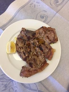 Bistecca grigliata con fetta di limone su piatto.