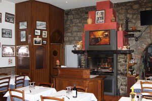 Interno di un ristorante con camino acceso e tavoli apparecchiati.
