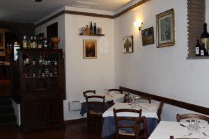 Interno di un ristorante con tavoli apparecchiati e credenza.