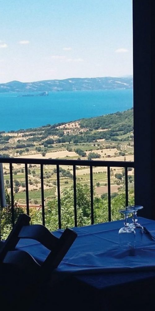 Tavolo da pranzo con vista su lago e colline.