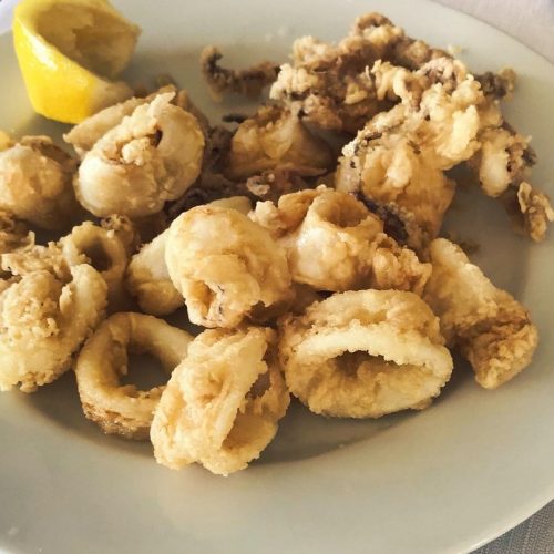 Calamari fritti su piatto con spicchio di limone.