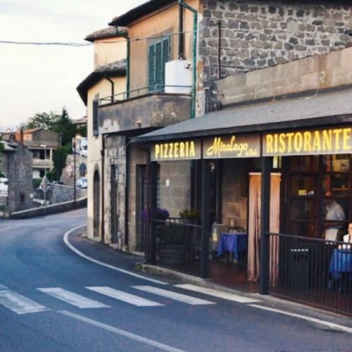 Strada curva con pizzeria e ristorante sulla destra.